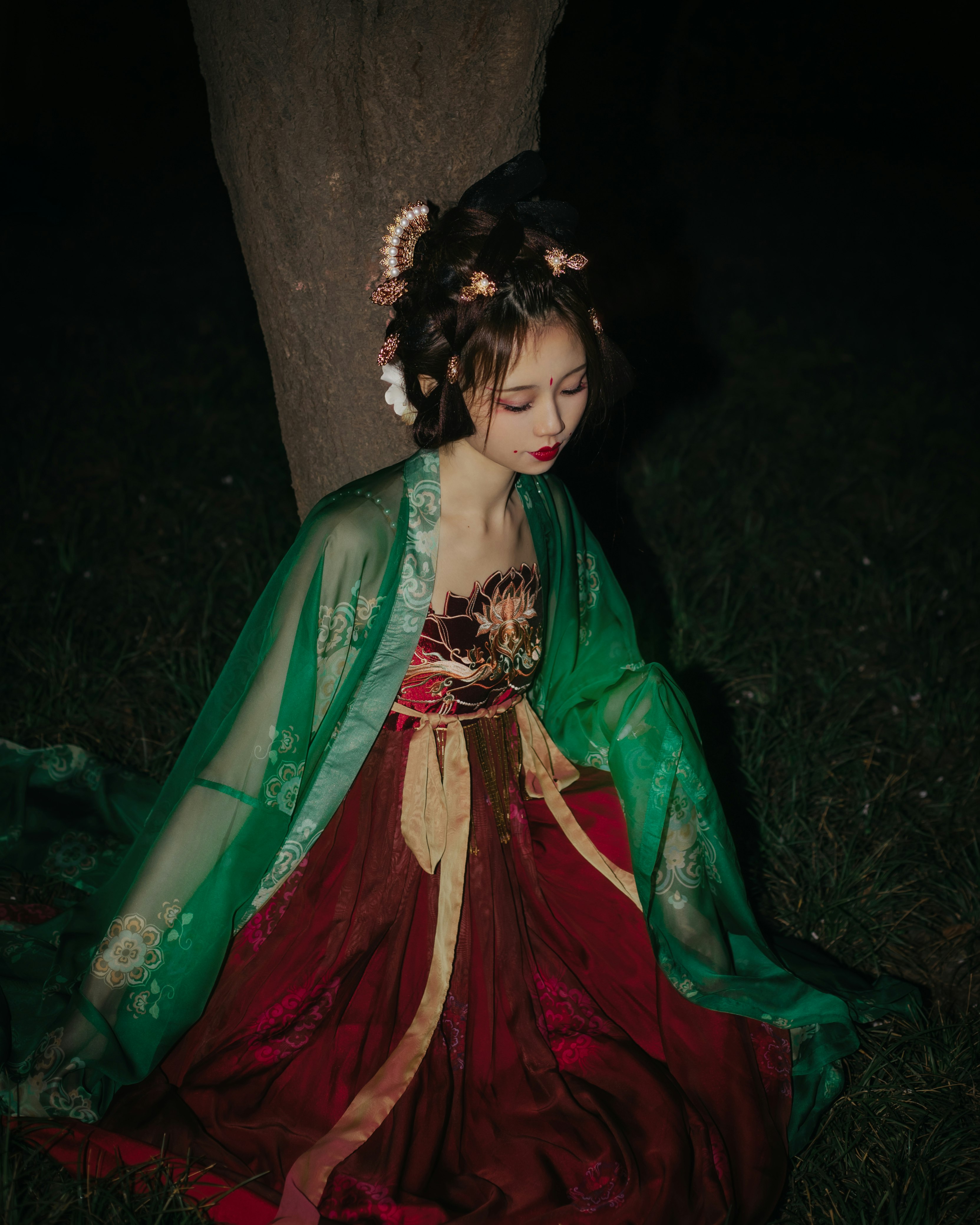 woman in green and red dress sitting on tree trunk